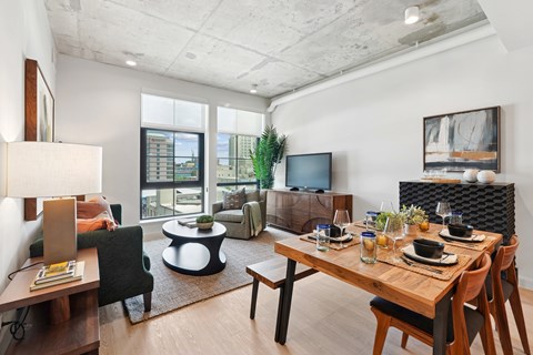 A modern living room with a wooden table set for a meal.