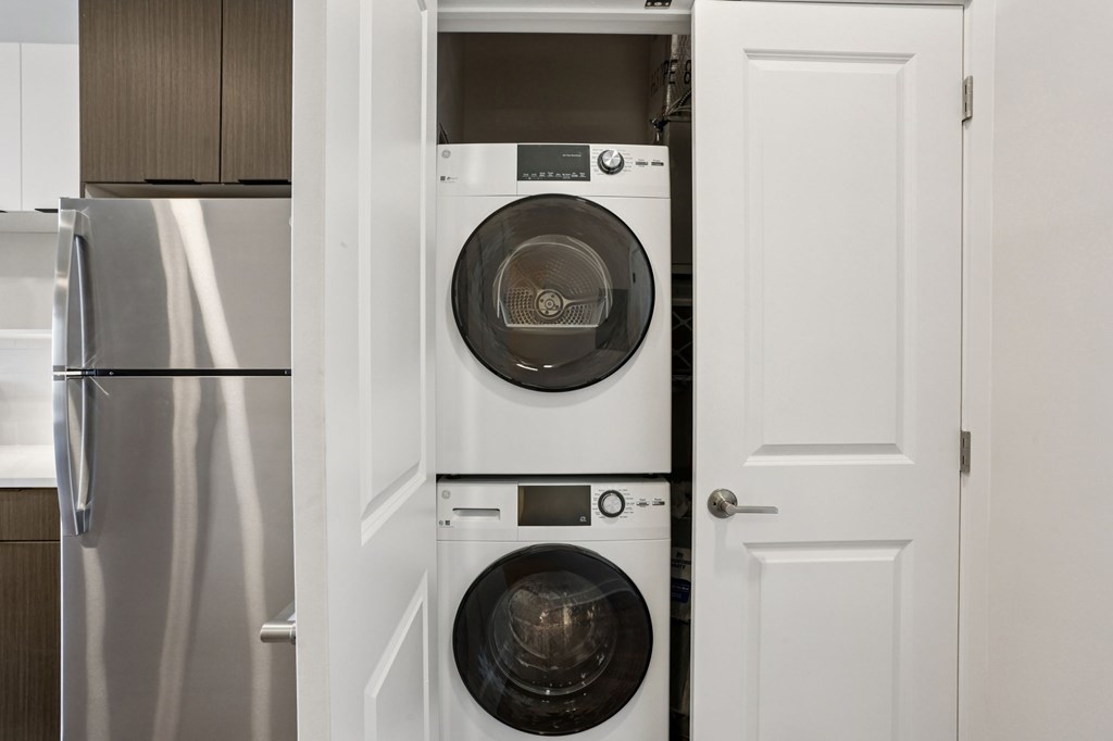 A white door is open to reveal a washing machine and dryer.