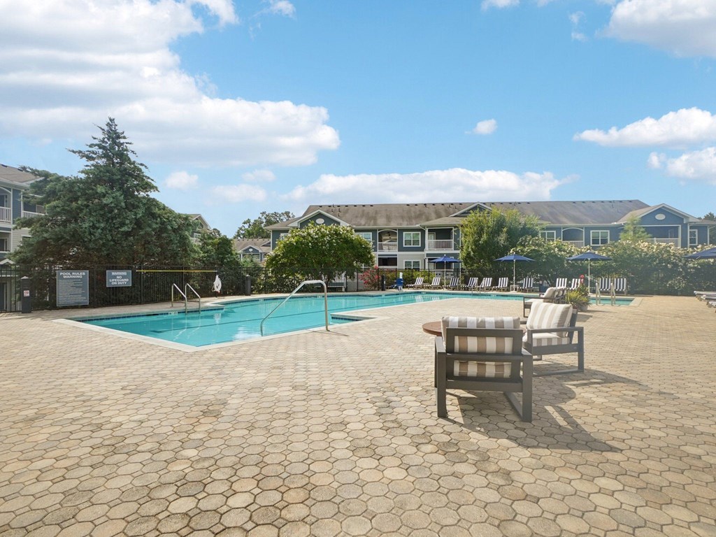 A pool area with a bench and a pool in the foreground.