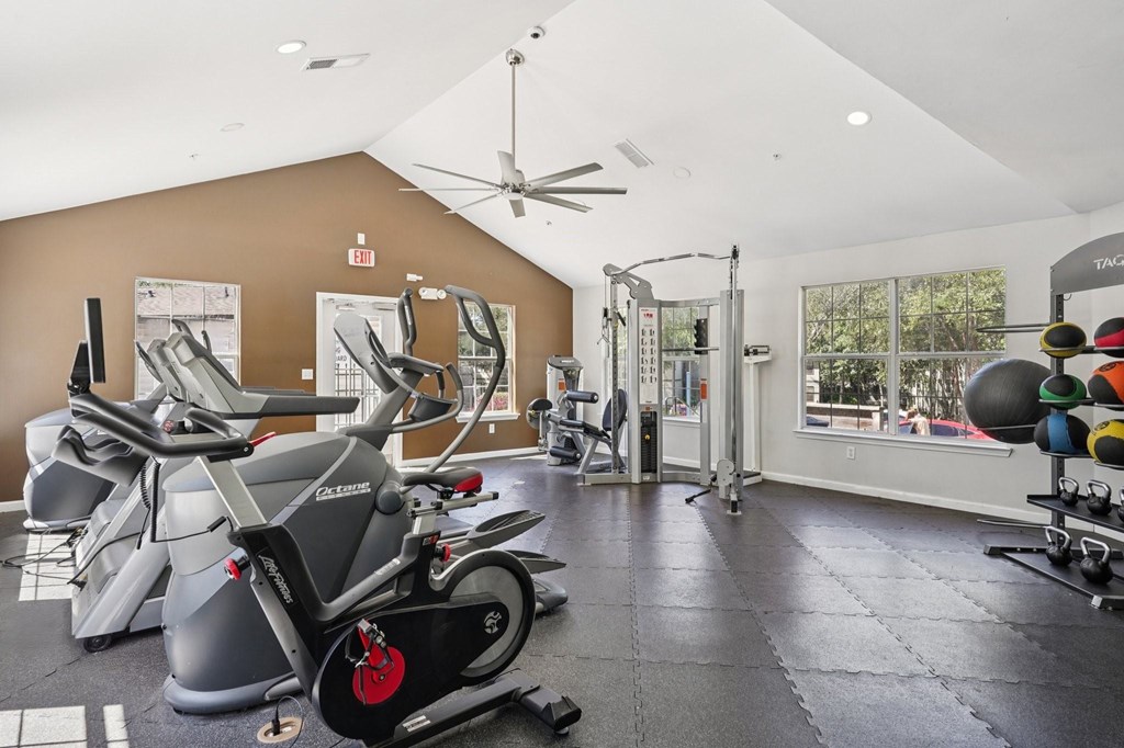 A gym with a variety of exercise equipment including treadmills, stationary bikes, and weight machines.