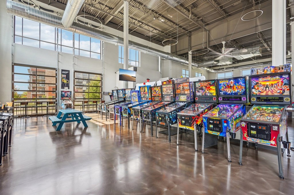 A row of arcade machines are lined up in a room with a concrete floor.