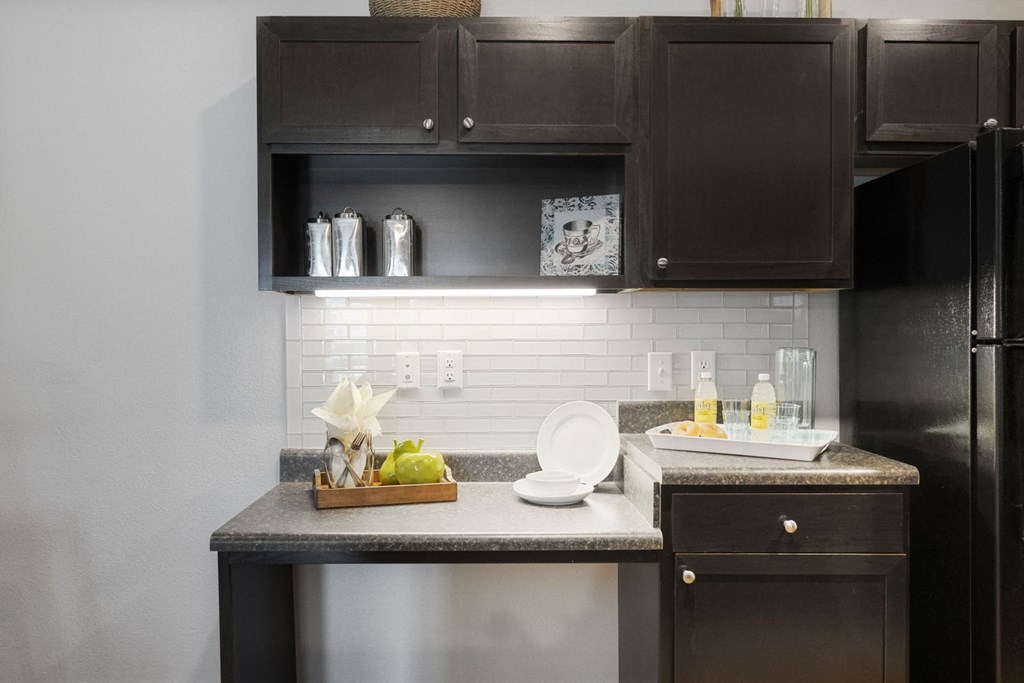 A kitchen with a black refrigerator and brown cabinets.