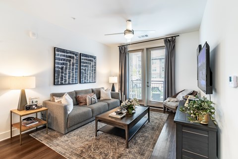 A living room with a grey couch, a coffee table, a television, and a large abstract painting on the wall.