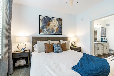 A bedroom with a large bed and a painting on the wall.