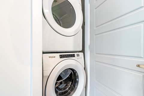 A white Whirlpool washing machine is installed in a white cabinet.