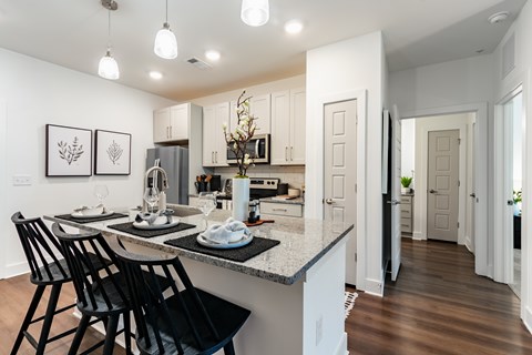A kitchen with a table and chairs in the foreground and a hallway in the background.