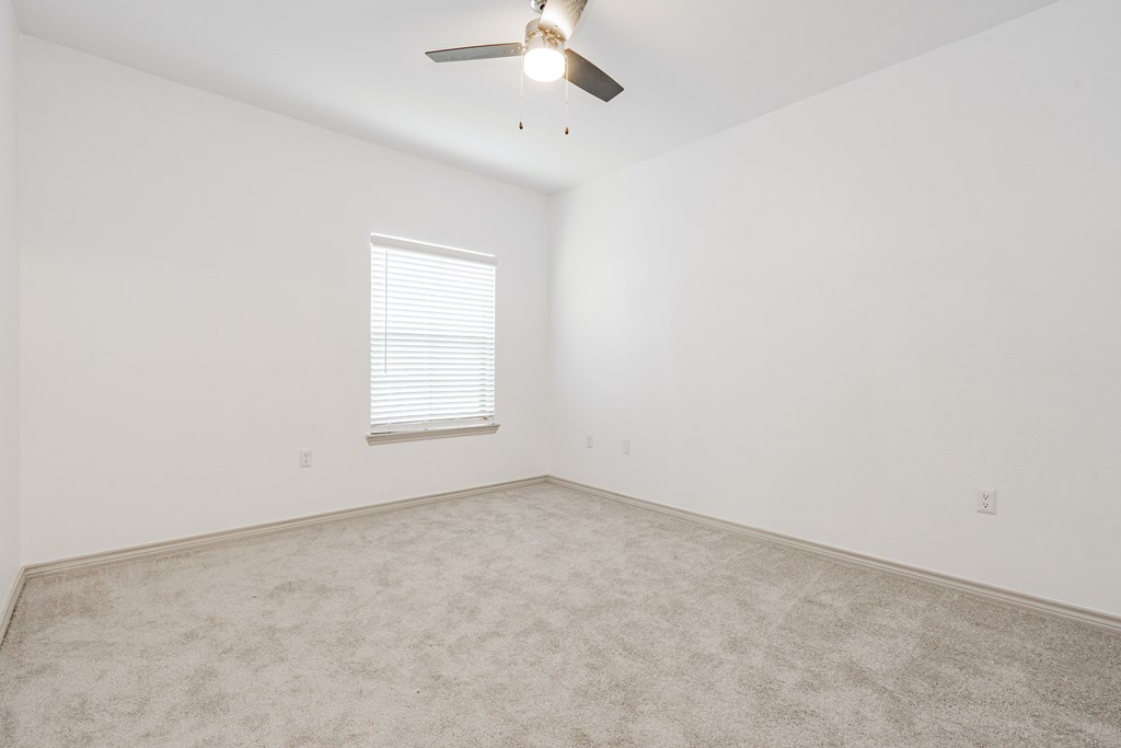 an empty room with a ceiling fan and a window