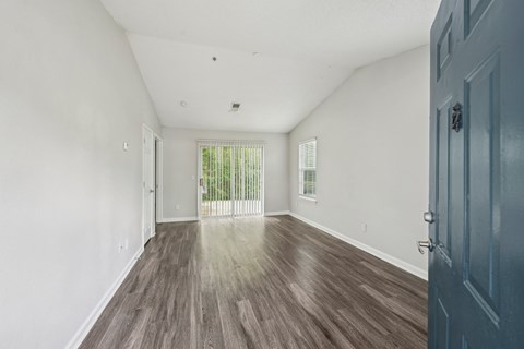 A room with a wooden floor and a door on the right side.