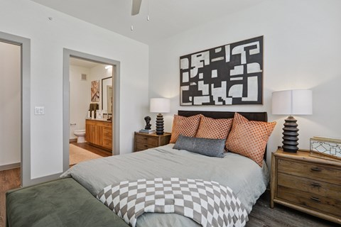 A bedroom with a large bed and a painting on the wall.