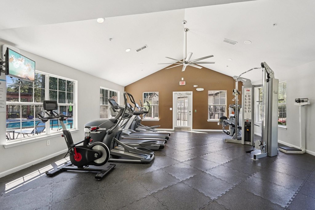 A gym with treadmills, elliptical machines, and a weight rack.