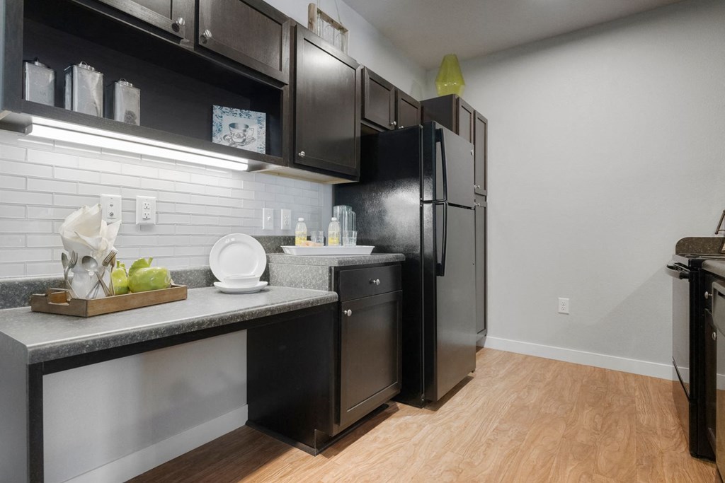 A kitchen with black cabinets and a black fridge.