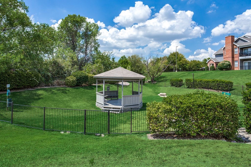 a gazebo in the middle of a yard with a fence