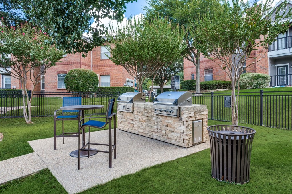 a patio with a grill and a table and chairs