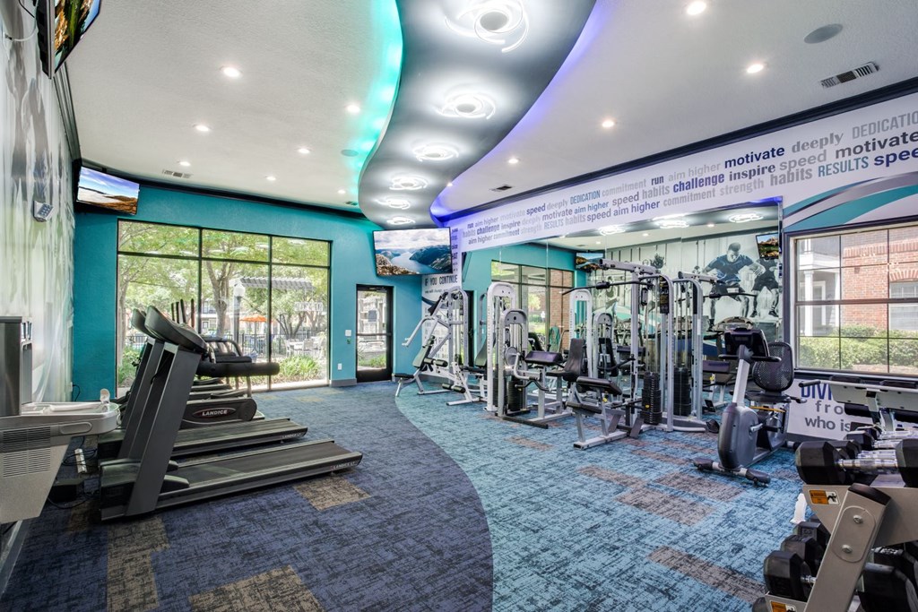 a gym with weights and cardio equipment in a building with windows