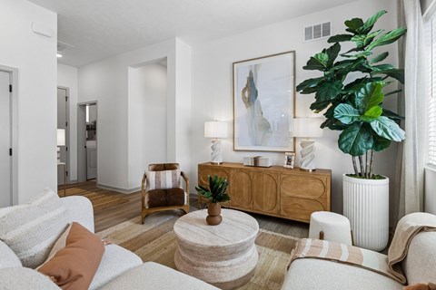 A living room with a white couch, a wooden side table, and a large painting on the wall.