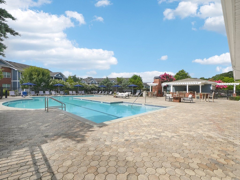 A large outdoor swimming pool surrounded by a brick patio.