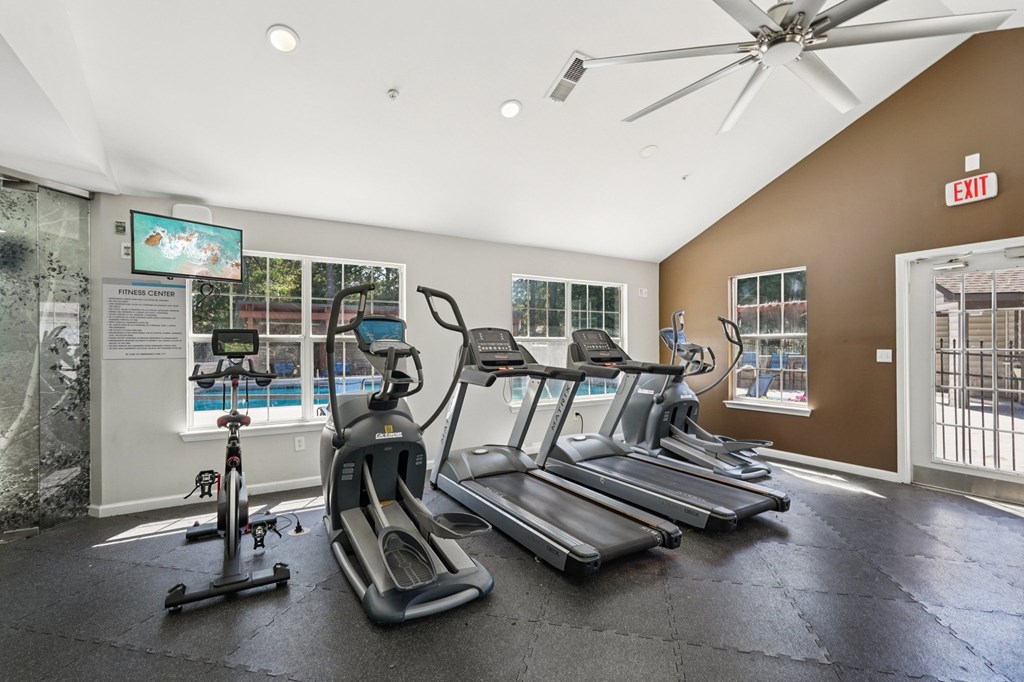 A gym with treadmills, elliptical machines, and a fan.