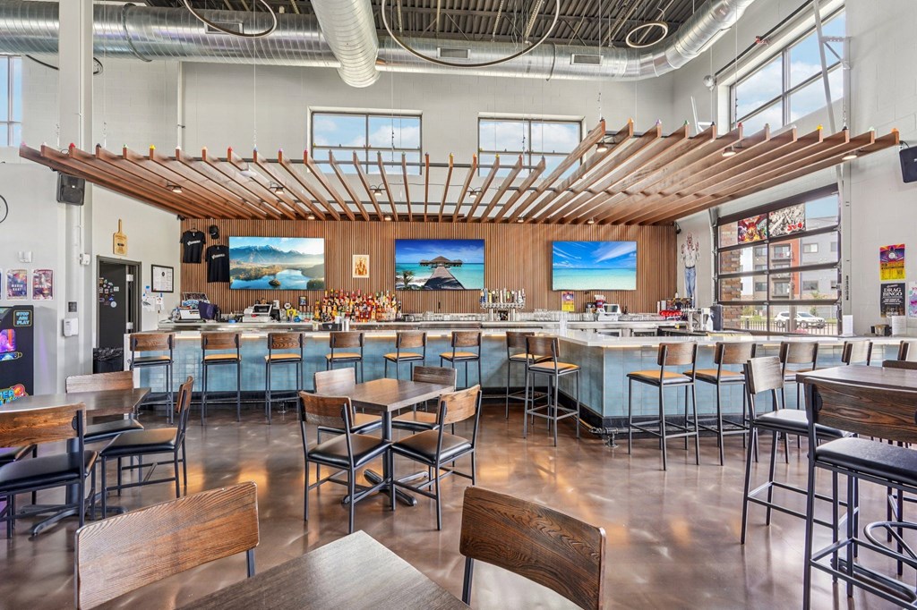 A modern restaurant with wooden tables and chairs and a bar area.