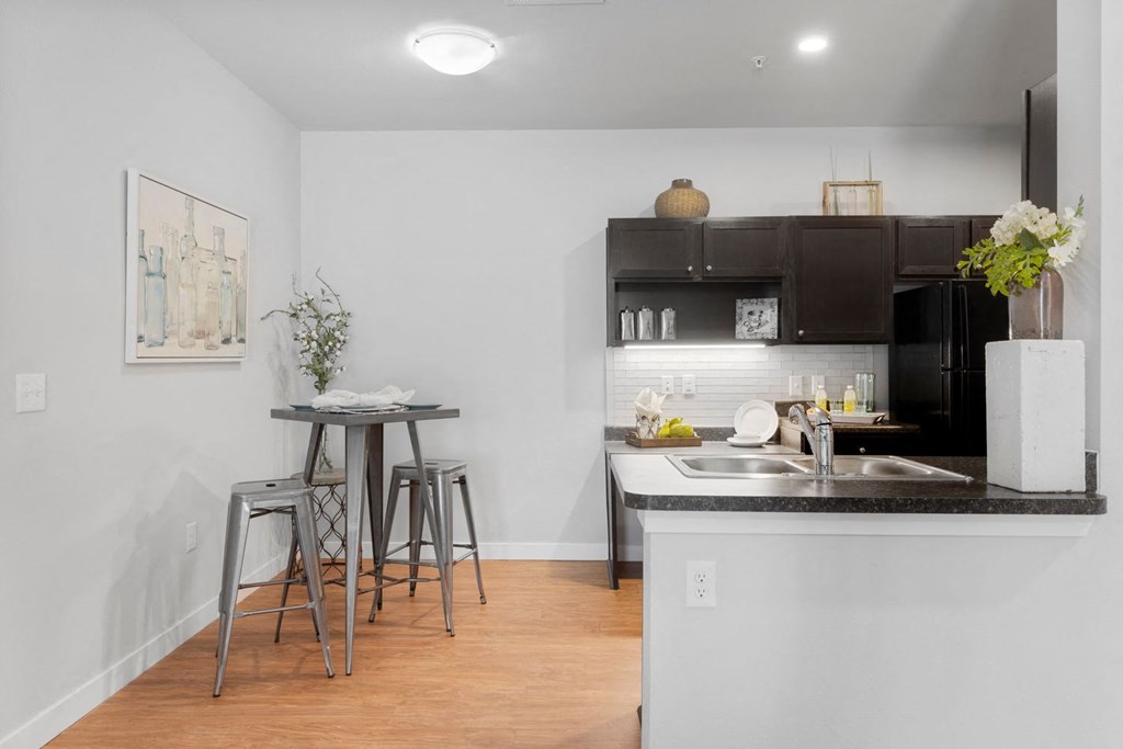 A kitchen with a table and chairs in front of it.