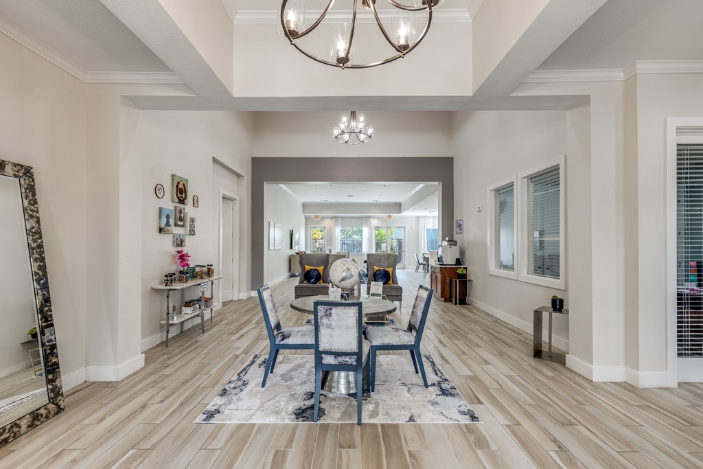 A dining room with a table set for four and a chandelier hanging from the ceiling.