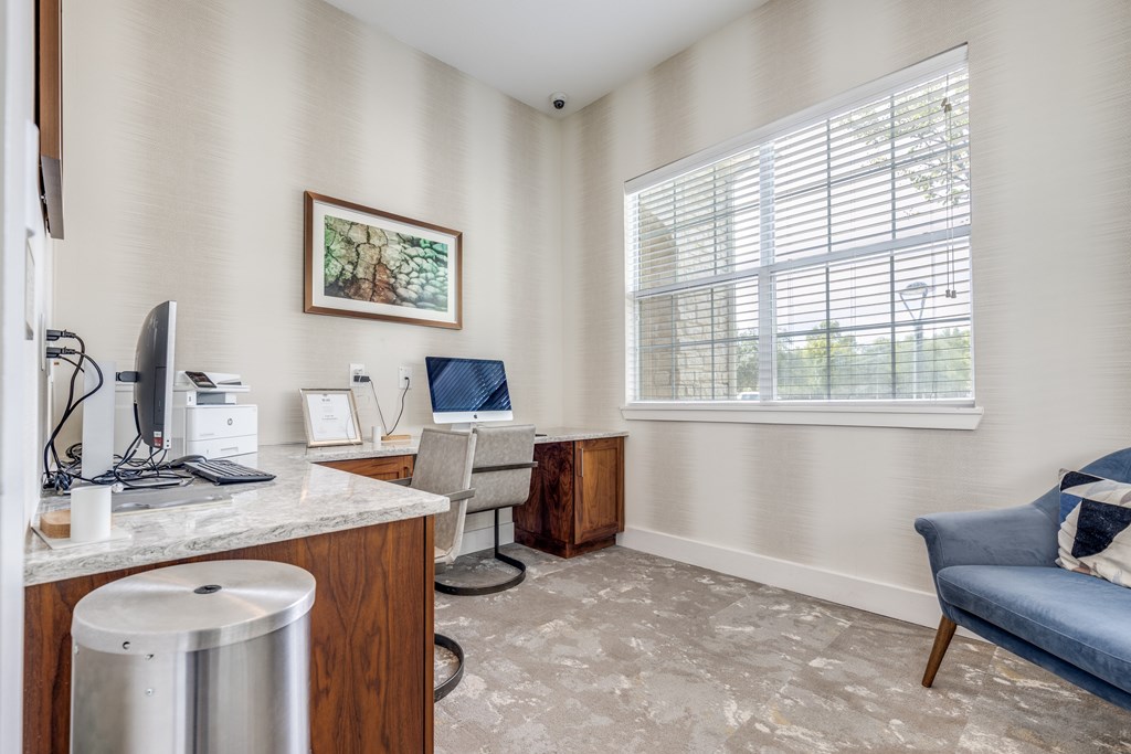 A room with a desk, chair, and a window with blinds.