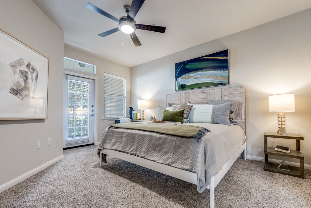 A bedroom with a bed, nightstand, and a ceiling fan.