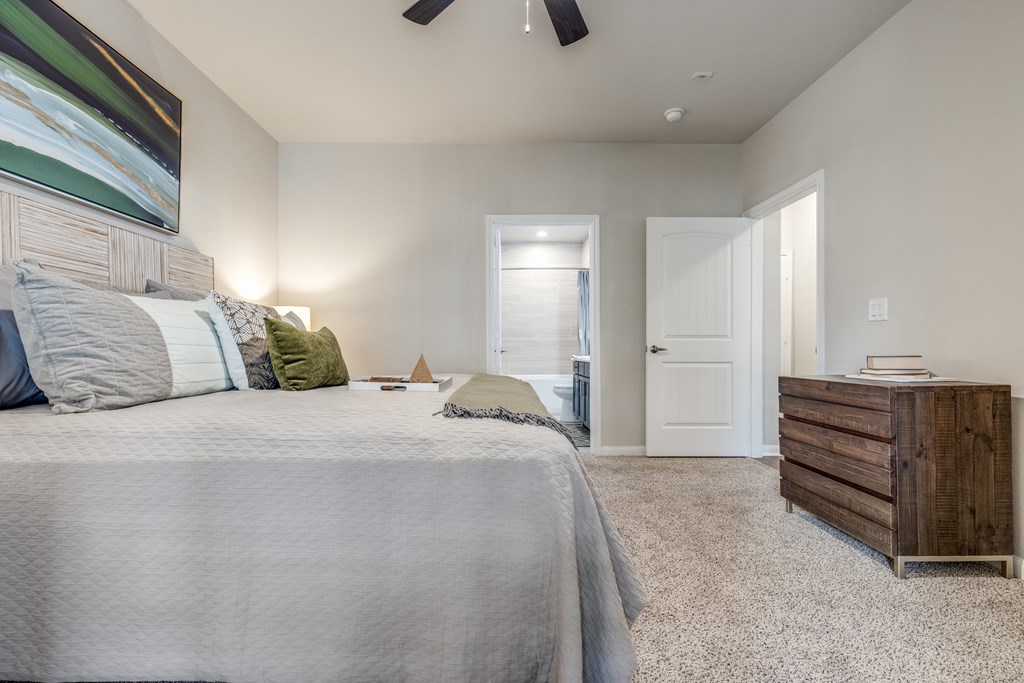 A bedroom with a large bed and a wooden dresser.