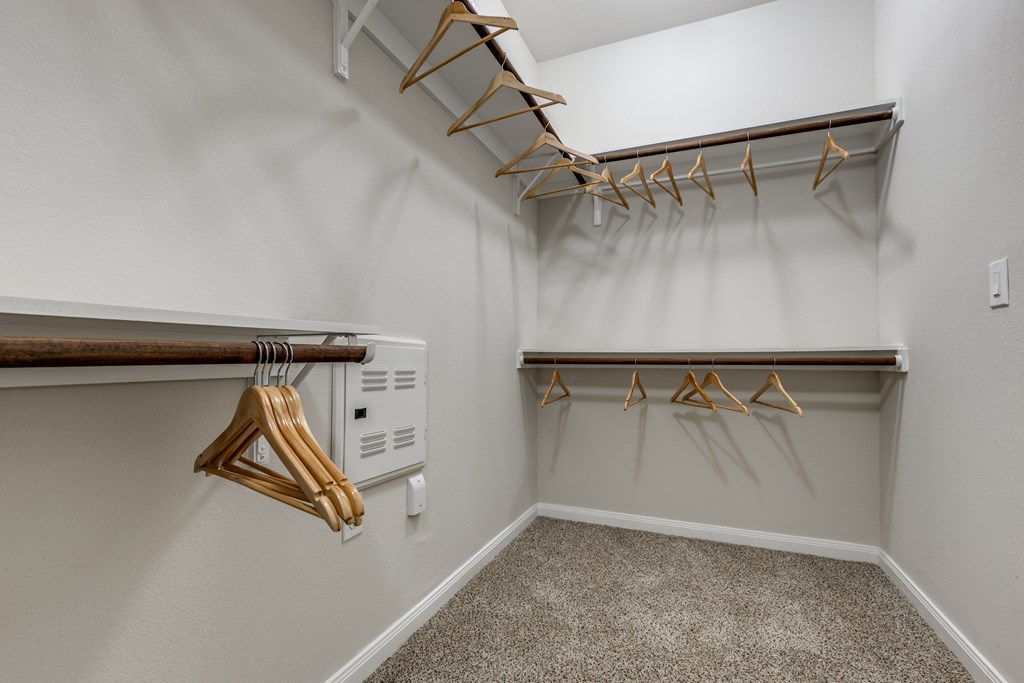 A white closet with two shelves and hangers.