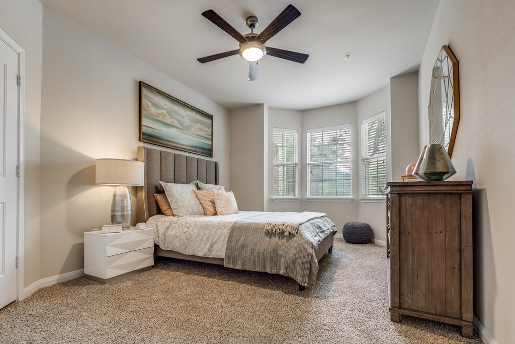 A bedroom with a bed, nightstand, and a ceiling fan.