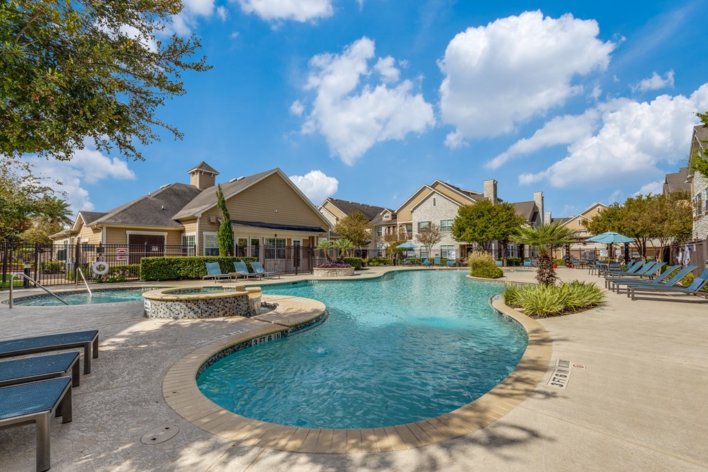 A large outdoor swimming pool surrounded by lounge chairs and trees.