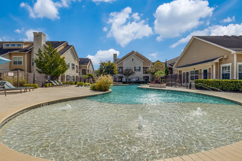 A large swimming pool with a fountain in the middle of a residential area.