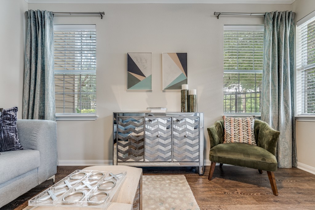 A living room with a grey couch, a green chair, and a patterned artwork on the wall.