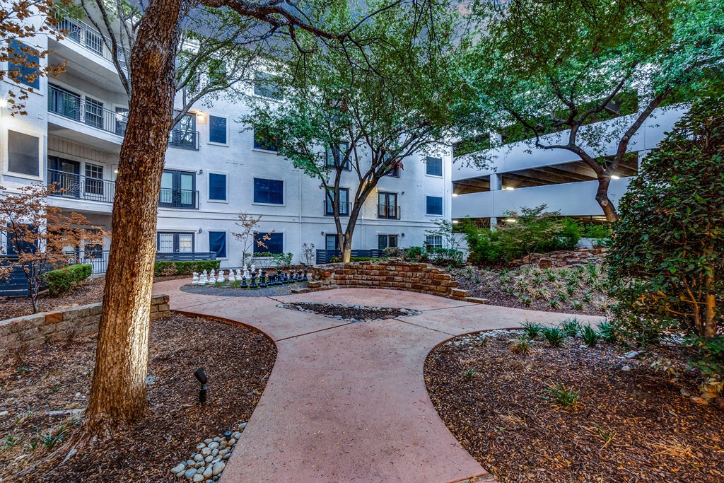 an outdoor courtyard with trees and a path in front of an apartment building