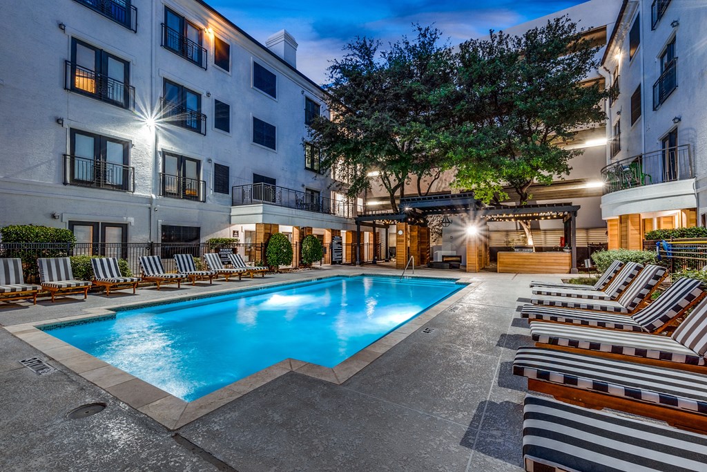 a swimming pool at night in front of an apartment building