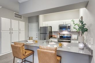 a kitchen with stainless steel appliances and a counter with chairs