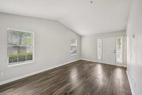 A room with wooden flooring and a window with blinds.