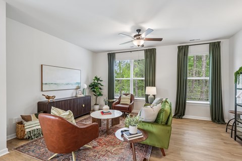 A living room with a brown chair, a green chair, a coffee table, and a ceiling fan.