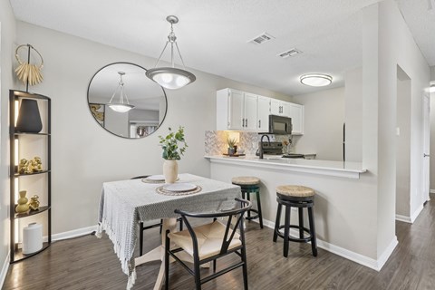 A dining area with a round mirror and a table with chairs.