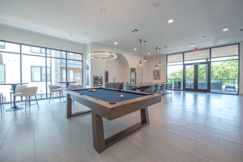 a billiards table in a clubhouse with a bar and tables