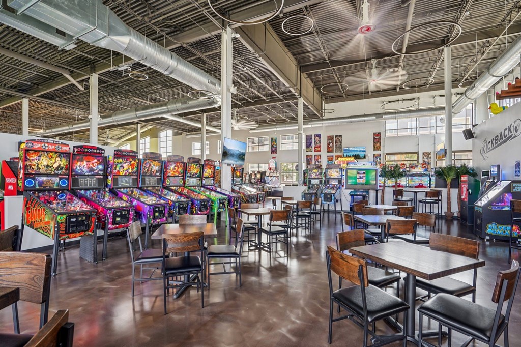A room with a lot of pinball machines and tables.