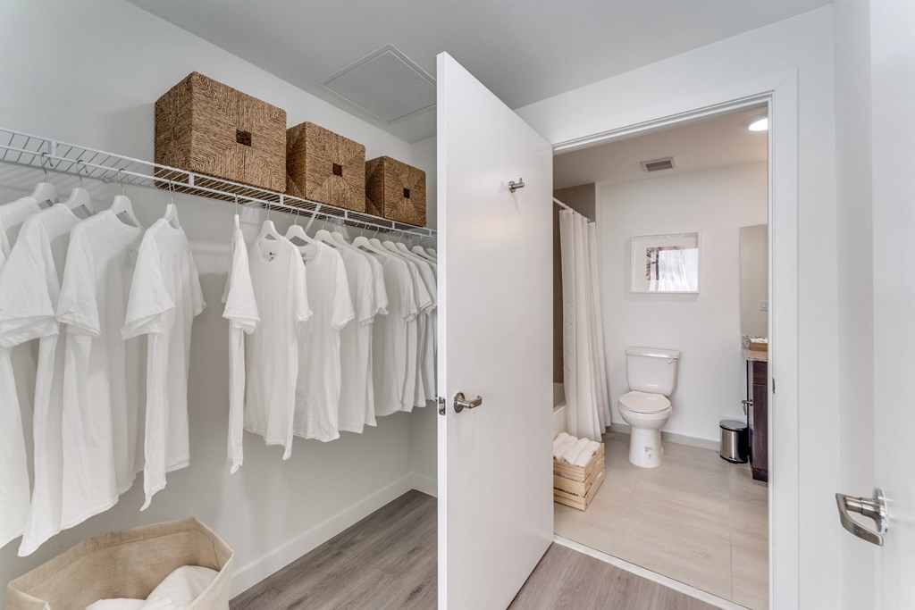 a closet with white clothes and a bathroom with a toilet