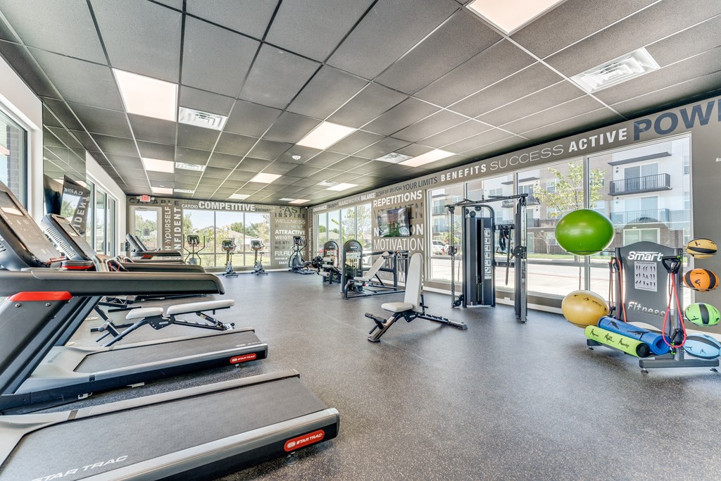 a gym with treadmills and other exercise equipment and glass walls