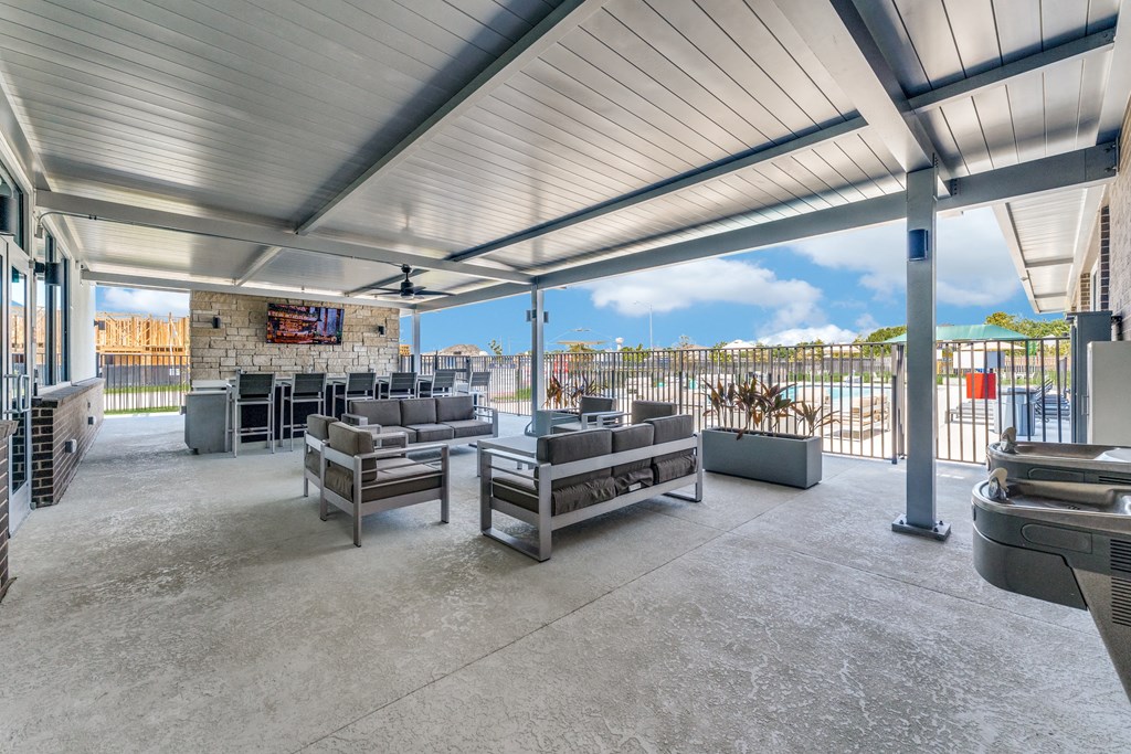 a covered patio with couches and chairs and a view of the ocean