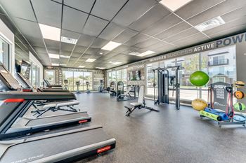 a gym with treadmills and other exercise equipment and glass walls