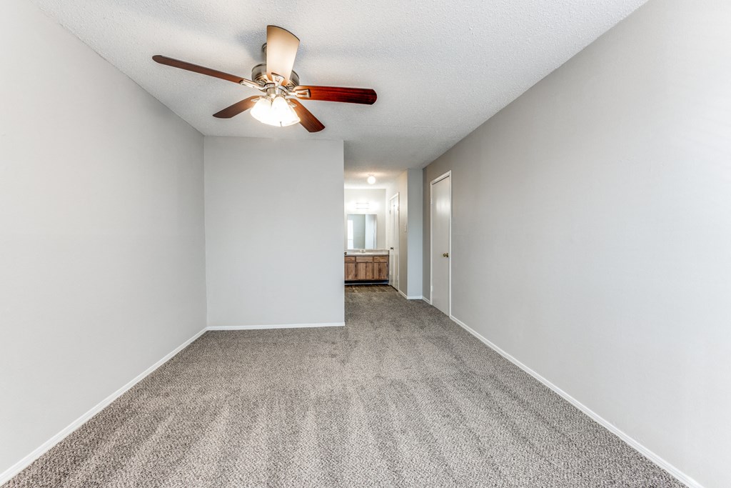 a spacious living room with white walls and a ceiling fan