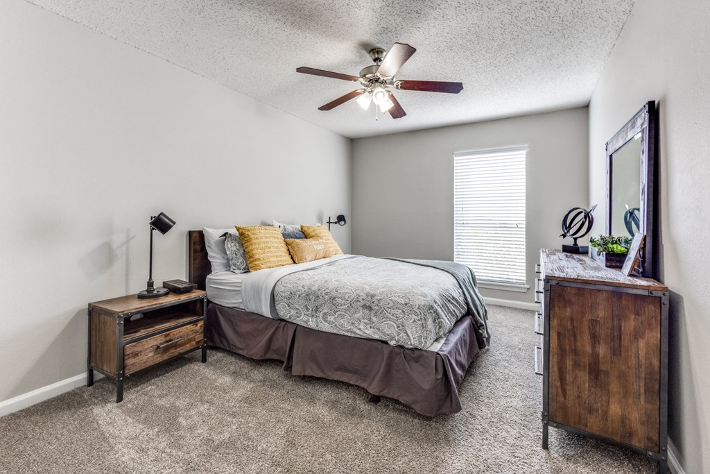 the master bedroom has a king sized bed and a ceiling fan