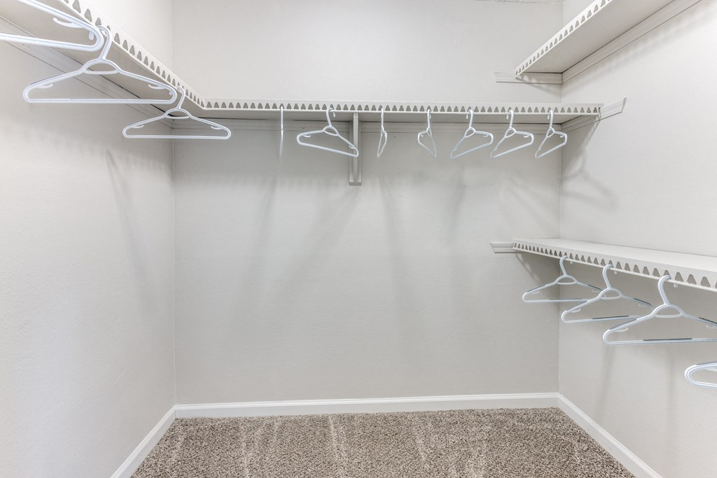 a walk in closet with white hooks and a shelf on the wall