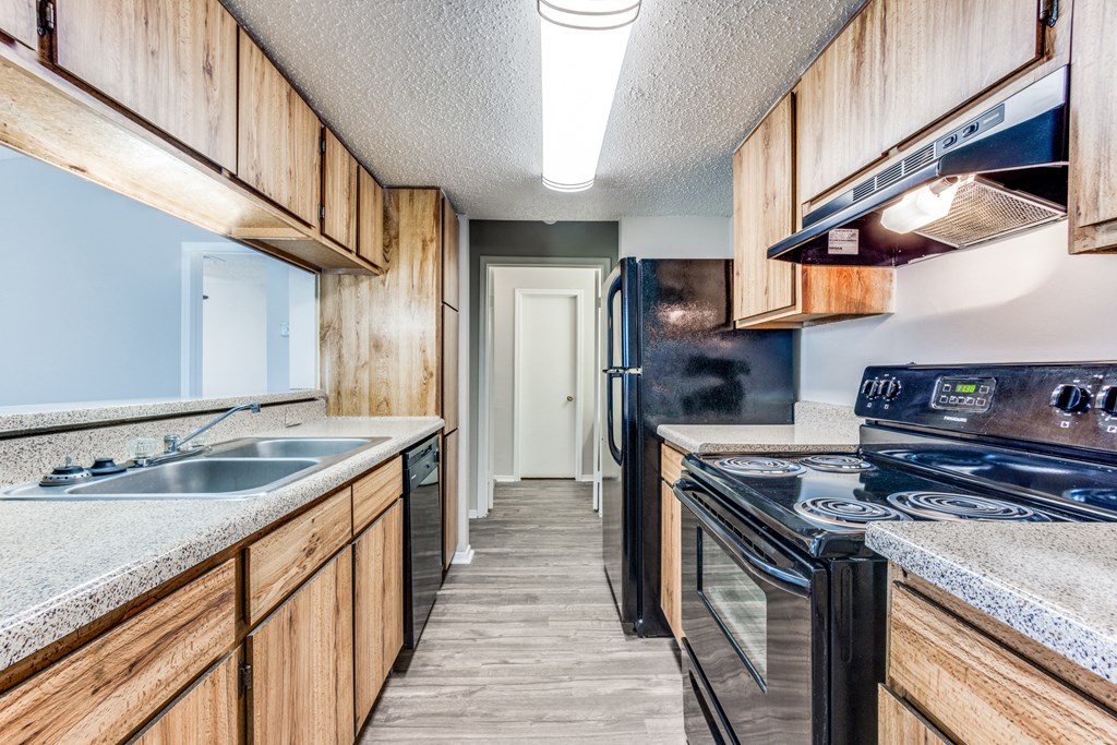 a kitchen with wood cabinets and black appliances and a sink