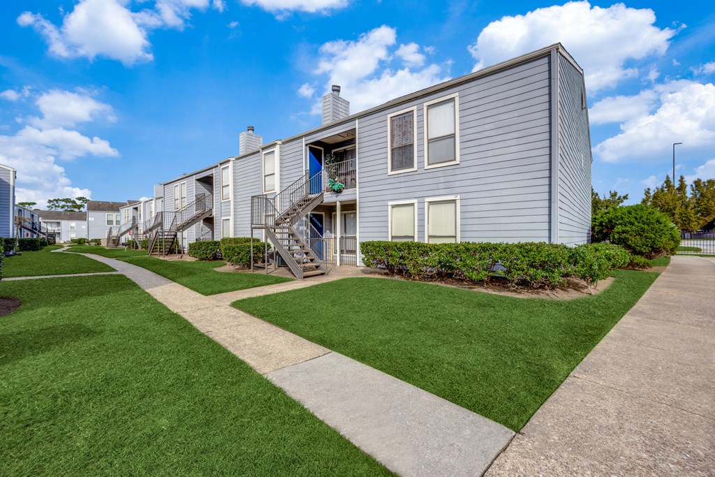 A modern building with a grey facade and a green lawn in front.