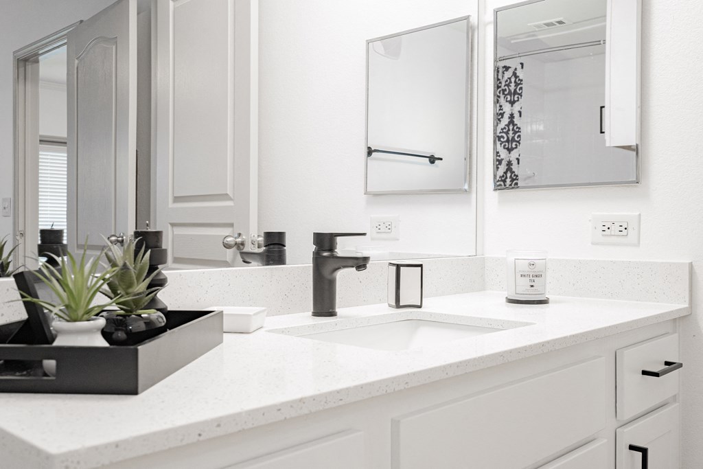 a white bathroom with a sink and two mirrors